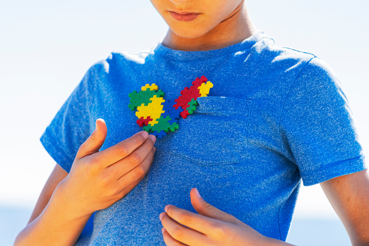 Boy Holding a Multicolored Puzzle Heart Against His Chest